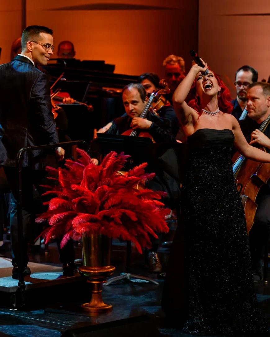 Monique Abbadie singing with the orchestra visible all around her.