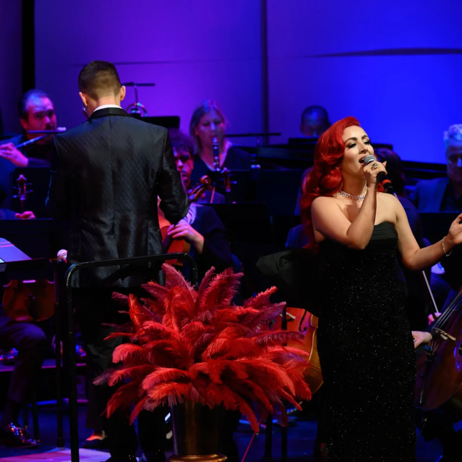 Monique Abbadie singing while the orchestra surrounds her.