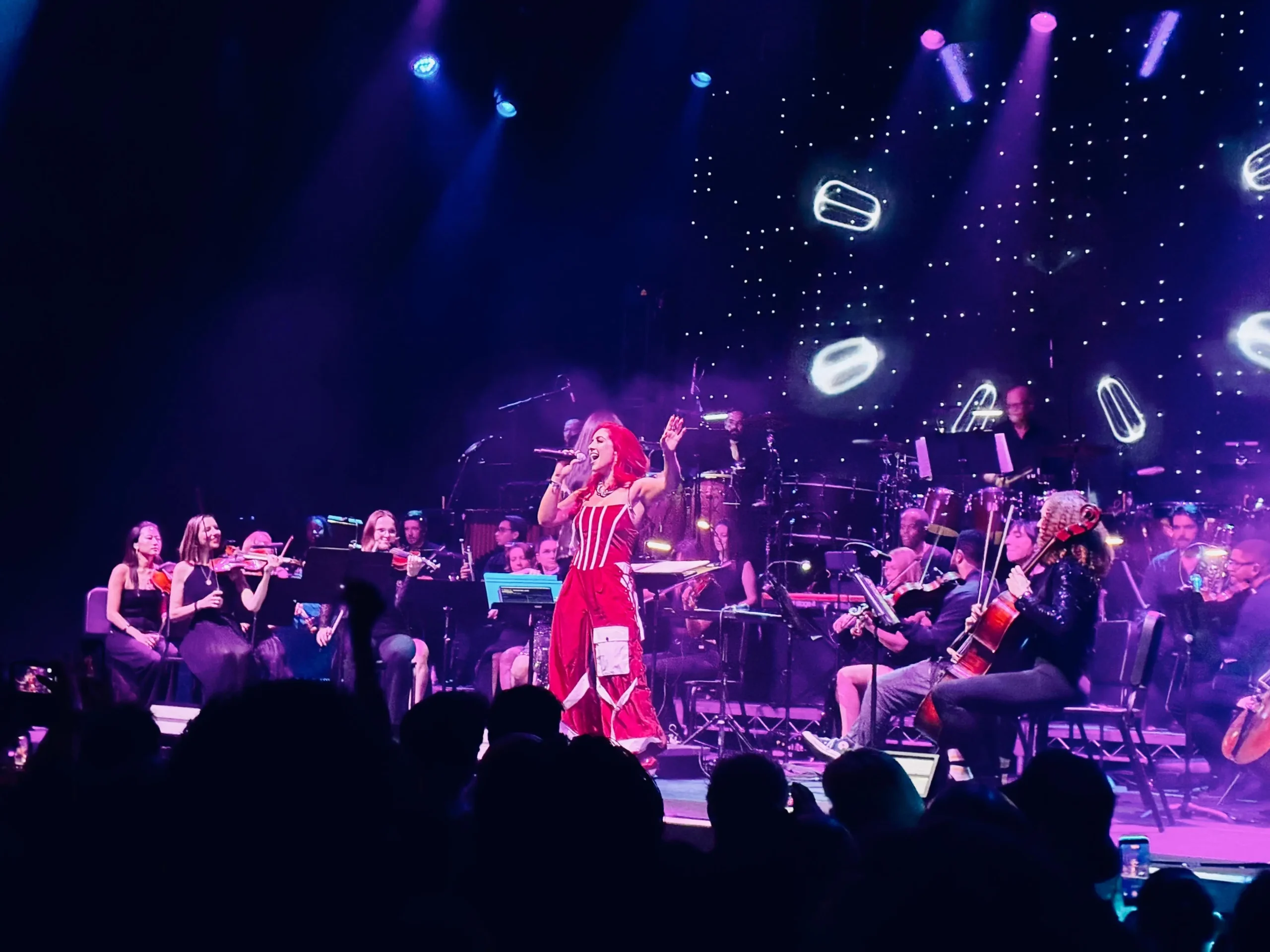Monique Abbadie singing before a lively crowd, with the orchestra backing her.