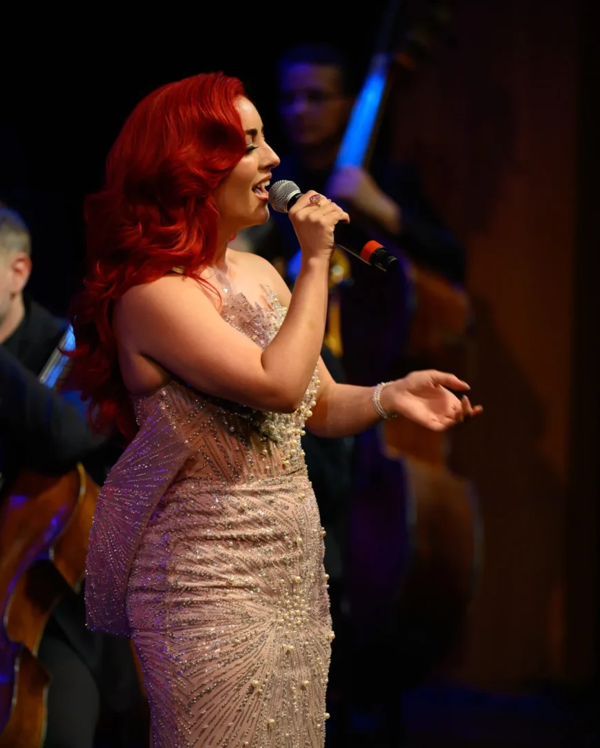Monique Abbadie performing while the orchestra plays behind her.