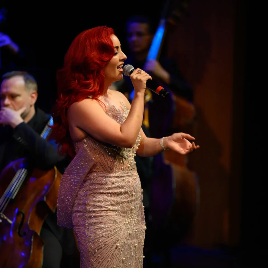 Monique Abbadie performing while the orchestra plays behind her.