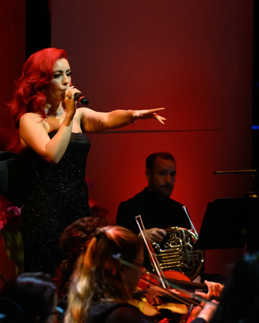 Monique Abbadie singing, one hand extended toward the audience.