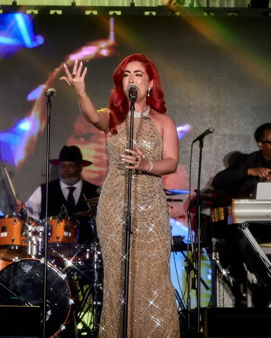 Monique Abbadie performing under stage lights at the Whitney E. Houston Foundation gala