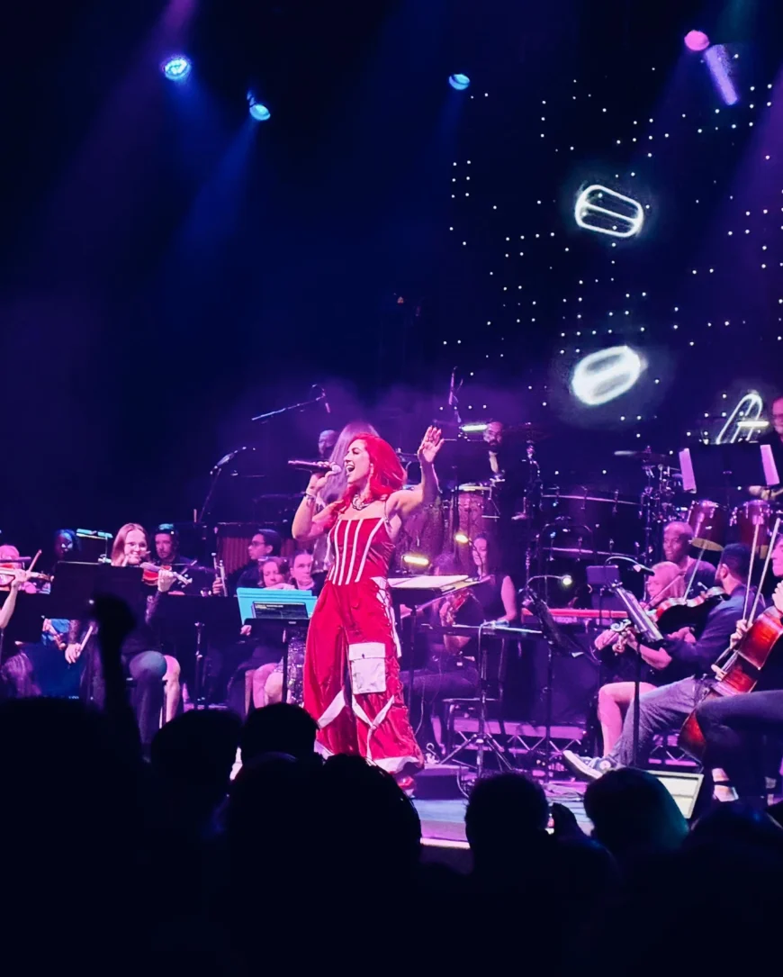Monique Abbadie singing before a lively crowd, with the orchestra backing her.